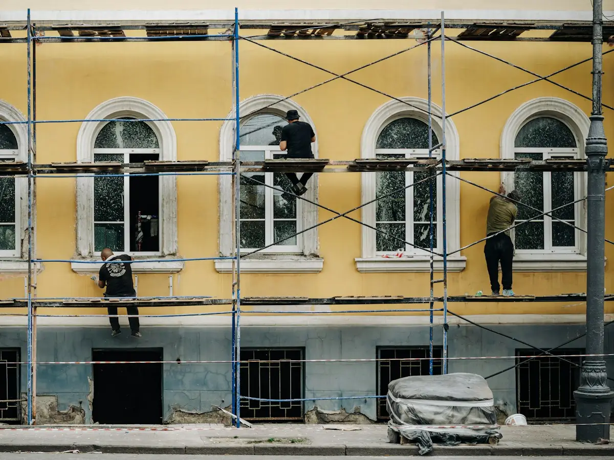 Állványon dolgozók egy sárga homlokzaton